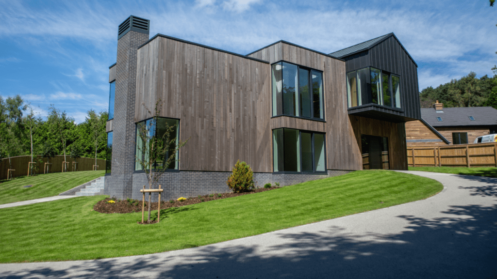 Modern timber frame home with timber cladding and landscaped lawn, showcasing quality residential design