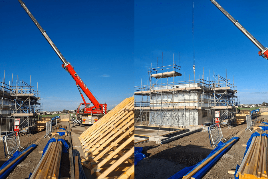 A red crane lifts materials over a low-carbon timber frame Newquay building frame for St Petrocs supported housing.